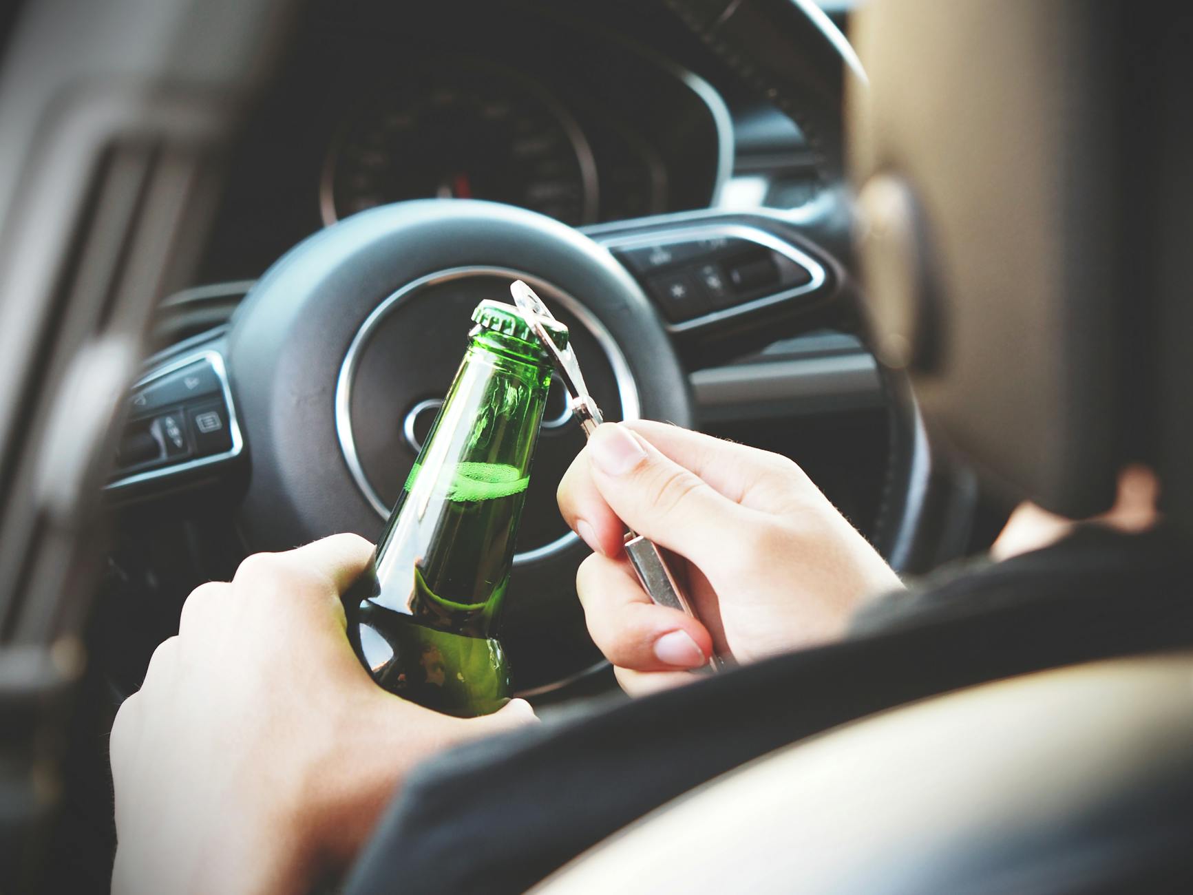 person opening bottle on car