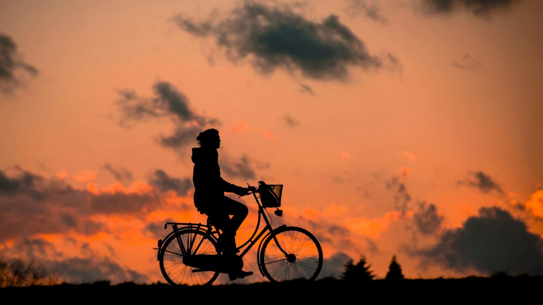 silhouette of person riding a bike during sunset